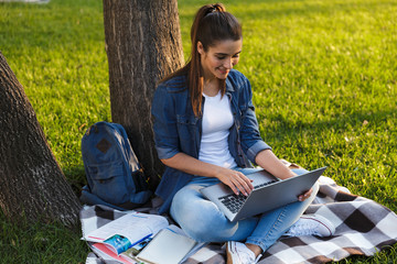 Poster - Beautiful young woman student in the park using laptop computer.