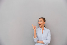 Business Woman Standing Over Grey Wall Background Posing Pointing To Copyspace.