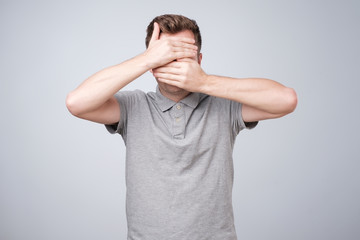 Wall Mural - Portrait of unrecognizable young man covering his face with hand, hiding his tears