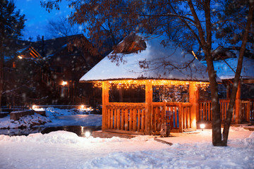 Beautiful gazebo decorated with bright garlands in winter