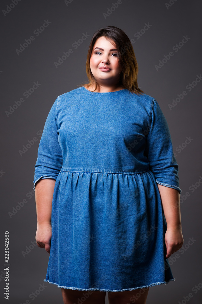 Plus size model in denim dress, fat woman on gray background, overweight  female body Stock Photo | Adobe Stock