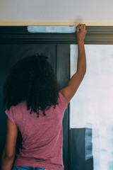 Wall Mural - Young black woman painting a wardrobe