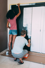 Wall Mural - Interracial couple painting a wardrobe