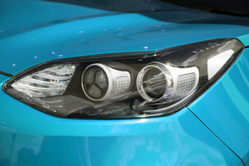 clean white headlight of a new blue luxury car from the saloon. close-up of the front right headligh