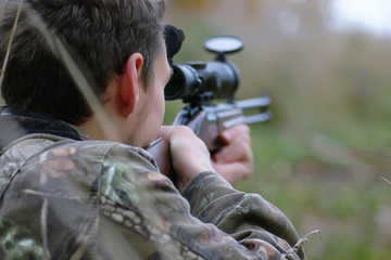 man in camouflage and with guns in a forest belt on a spring hun