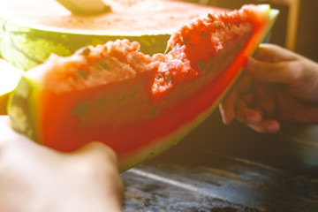 Wall Mural - toned image of teenager male eating holding piece of watermelon on the wooden table summer d