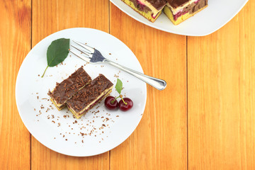 Cocoa cherry cake, called 'Danube Wave'. Top with vanilla cream and chocolate. Plate with two slices of cake on the wooden table. Top view image