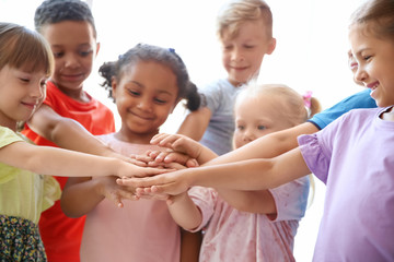 Wall Mural - Little children putting their hands together on light background. Unity concept