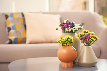 Canvas Print - Beautiful flowers in vases as element of interior design on table. Space for text