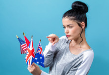 Young Woman With Learn English Theme With The Flags Of English Speaking Countries On A Blue Background