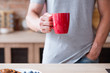 © golubovy - traditional morning hot beverage. quick and easy breakfast. man holding tea or instant coffee drink in a red mug standing in the kitchen.