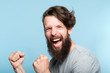 © golubovy - victory success and achievement. excited thrilled agitated guy making a winner gesture. hipster man portrait on blue background. emotional reaction and facial expression concept.