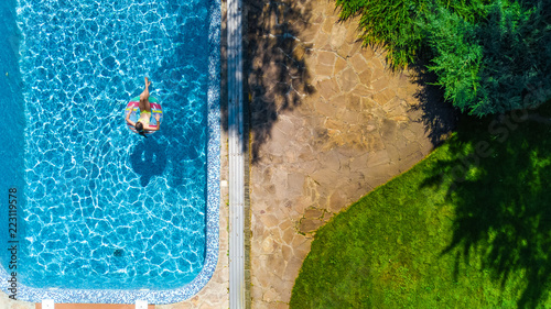 Obraz na płótnie Widok z lotu ptaka drone mała dziewczynka w basenie z góry, dziecko pływa na nadmuchiwane pierścień pączek, dziecko ma zabawy w niebieski wody na rodzinne wakacje
