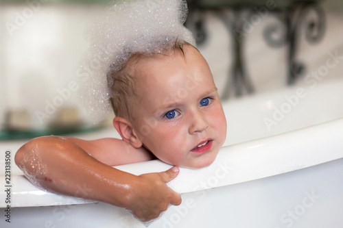 Cute Caucasian Kid With Blue Eyes And Blonde Hair In The Bathtube