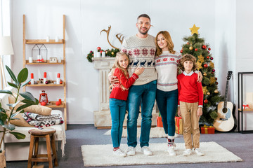 happy young family embracing on christmas at home and looking at camera