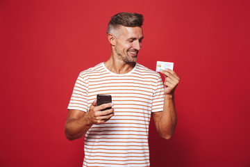 Wall Mural - Portrait of a delighted man standing over red background
