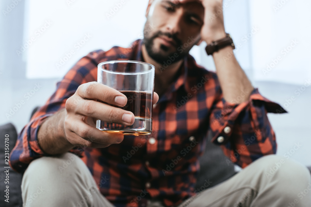 close-up shot of depressed young man with glass of whiskey - obrazy, fototapety, plakaty 