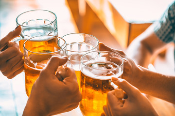 Friends toasting with glasses of light beer at the pub. Beautiful background of the Oktoberfest. A group of young people while relaxing at the bar. fine grain. Soft focus. Shallow DOF