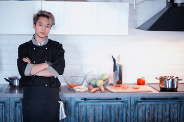 Asian cook in the kitchen prepares food in a cook suit