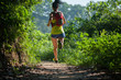 Young woman trail runner running on tropical forest trail during morning