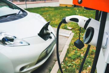 Charging an electric car with the power cable supply plugged in.