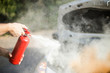 A person who sprays from a fire extinguisher over a vehicle in flame