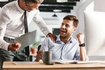 Fototapete - Happy emotional men colleagues in office working with computer.