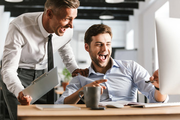 Fototapete - Happy emotional men colleagues in office working with computer.