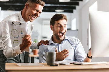 Fototapete - Happy emotional men colleagues in office working with computer.