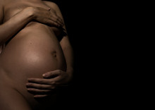 Belly Of A Pregnant Woman On A Black Background