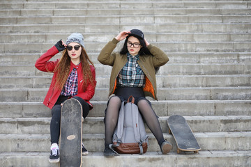 A young hipster girl is riding a skateboard. Girls girlfriends f