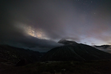 Wall Mural - wanderlust by night on the alps with clouds and fog. snowy mountains starry sky, summer adventure ex