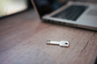© bnenin - Silver colored USB-stick shaped like a key on a wooden table near the laptop.