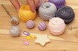 Colorful yarn, fingers and crochet hook on wooden background