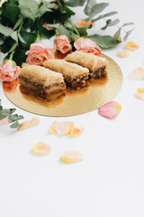 Wall Mural - Baklava sweet dessert and pink roses. Pastry made of layers of filo filled with chopped nuts and sweetened and held together with syrup or hone