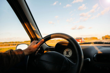 Wall Mural -  driver of the car travels behind the wheel on a sunny day. a trip outside the city to nature.