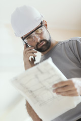 Wall Mural - Professional construction worker checking a project and calling