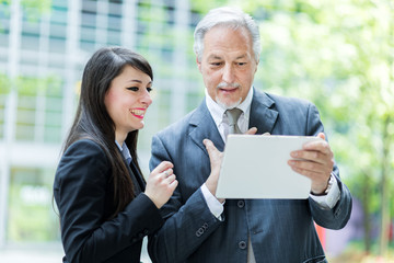 Wall Mural - Couple of business people using a tablet outdoor