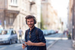 © Novak - Portrait of young man listening music via headphones at urban street
