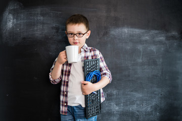 Young boy's standing with keyboard and network wire near blackboard. Young programmer or system administrator. Creative design concept for 2019 calendar.