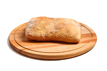 traditional italian wheat bread ciabatta on a round wooden cutting board.   isolated on white background