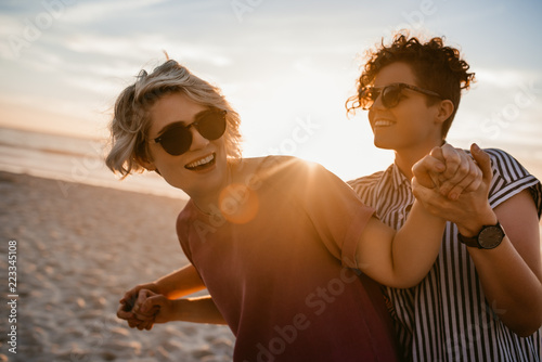 Fotografía Laughing lesbian couple dancing together on a beach at sunset