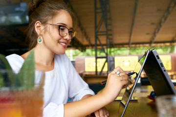 Fototapete - Freelancer mixed race woman hand pointing with stylus on convertible laptop screen in tent mode. Asian caucasian girl using 2 in 1 notebook with touchscreen for drawing and work on design project.