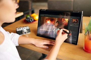 Fototapete - Freelancer retoucher woman works on convertible laptop computer with photo editing software using stylus. Photographer or designer digital image processing. 2 in 1 with touch screen in tent mode.