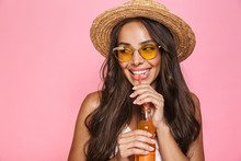 Photo Closeup Of European Woman 20s Wearing Sunglasses And Straw Hat Drinking Juice From Glass Bottle, Isolated Over Pink Background