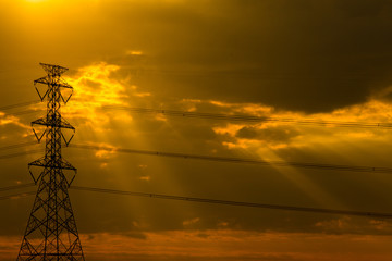 Silhouette of high voltage power line cables in an orange evening sunset