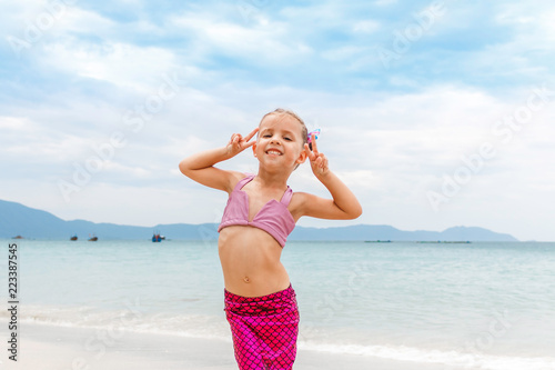 Fotomural Little beautiful girl dressed in swimsuit as a mermaid stay on the seashore
