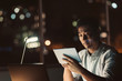 © mavoimages - Young Asian businessman working on a tablet late at night