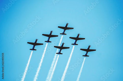 Fotografija Squad of six airplanes flying together leaving a smoke trail behind going up on the sky