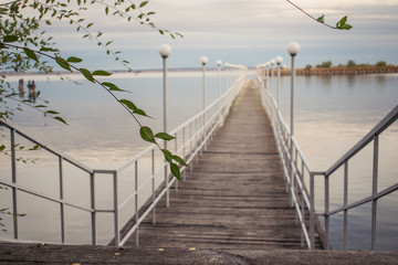  Perspective view of a wooden pier on the pond at sunset with seagulls